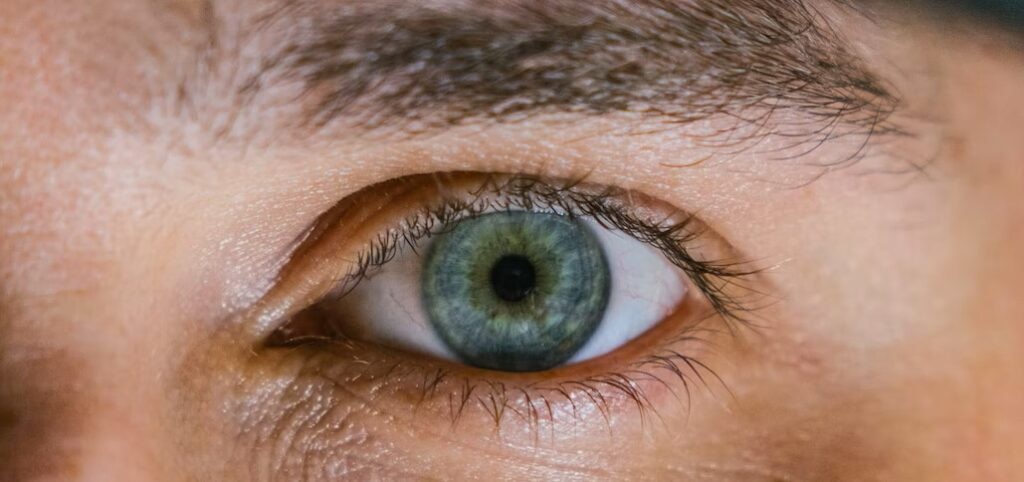 Extreme close-up of a blue eye, showing a bit of hazel around the middle of the iris.