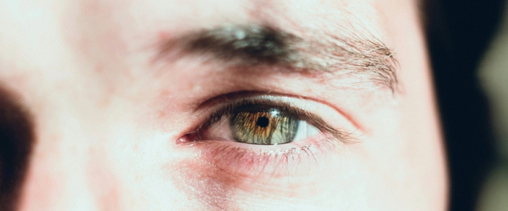 A close-up of a man’s hazel eye, rich brown at the centre and fading to green around the outer edge.