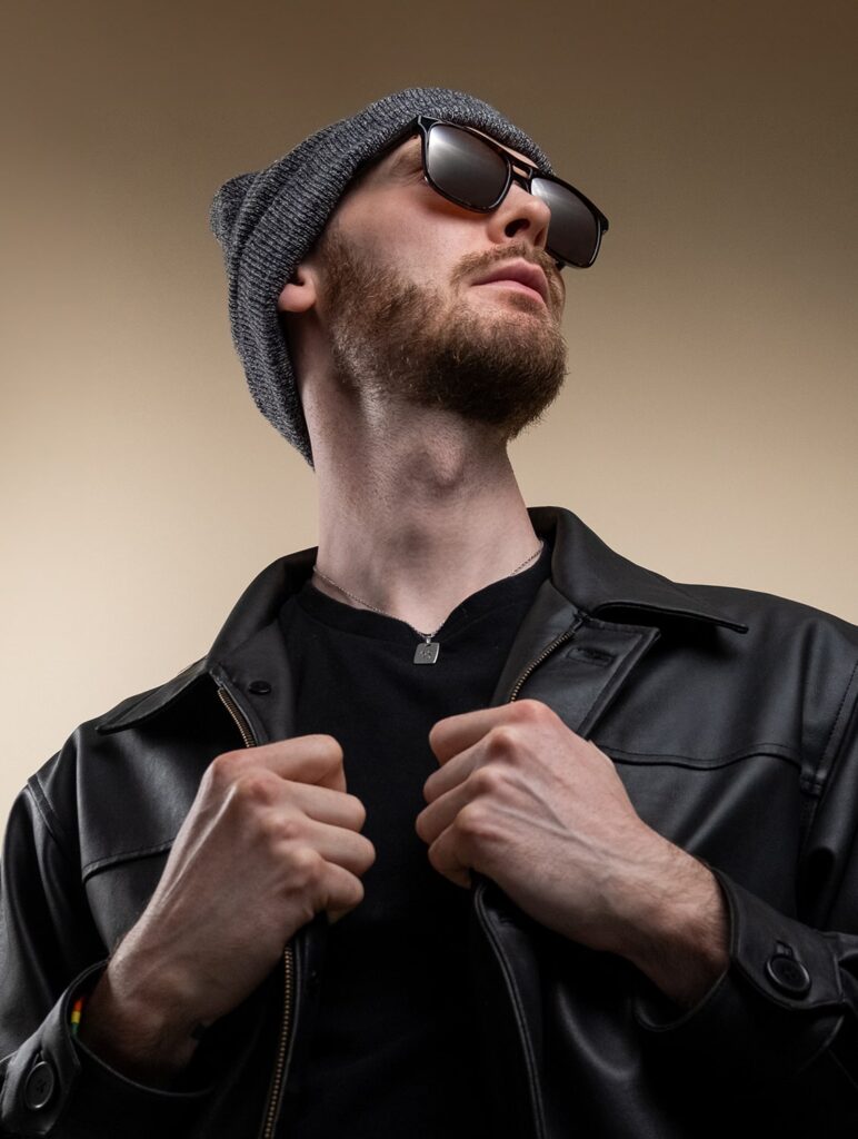 Man posing with a pair of sunglasses and beanie hat looking to the right