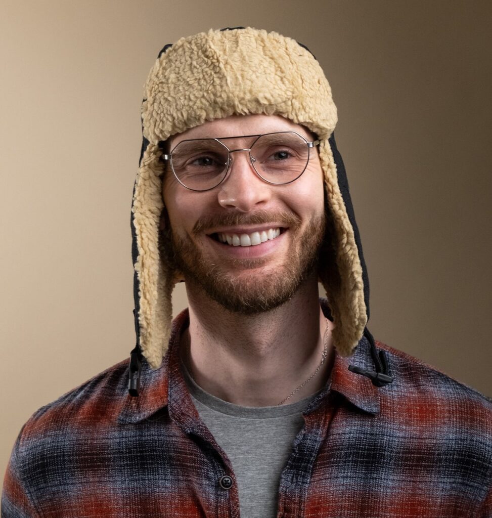 Man posing with metal frame glasses wearing an aviator hat