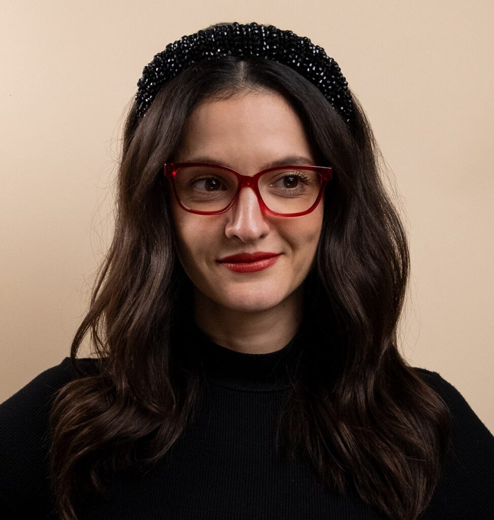 Woman wearing red frames and a winter headband looking to the right