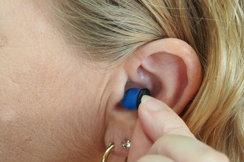 Close-up of an in-ear hearing aid being inserted into a woman's ear