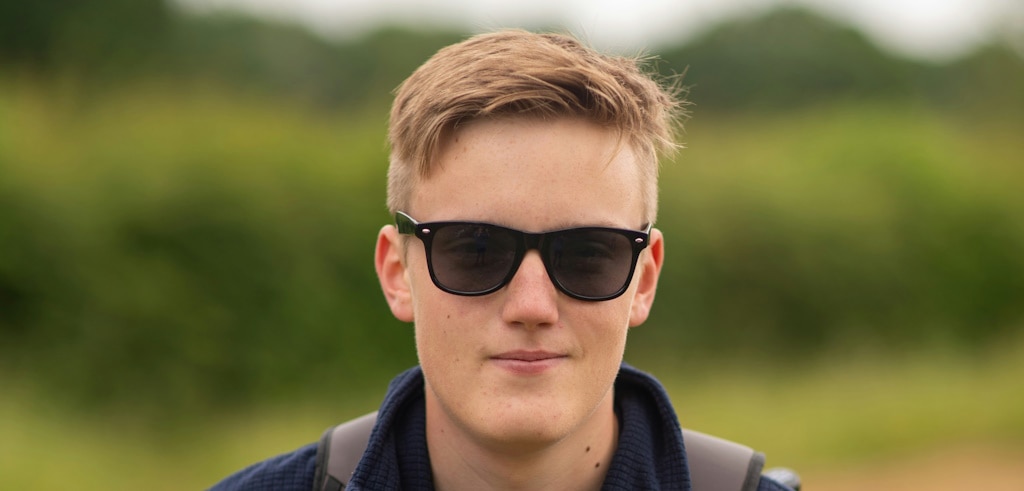 A young man with a blond undercut wearing Wayfarer sunglasses outdoors