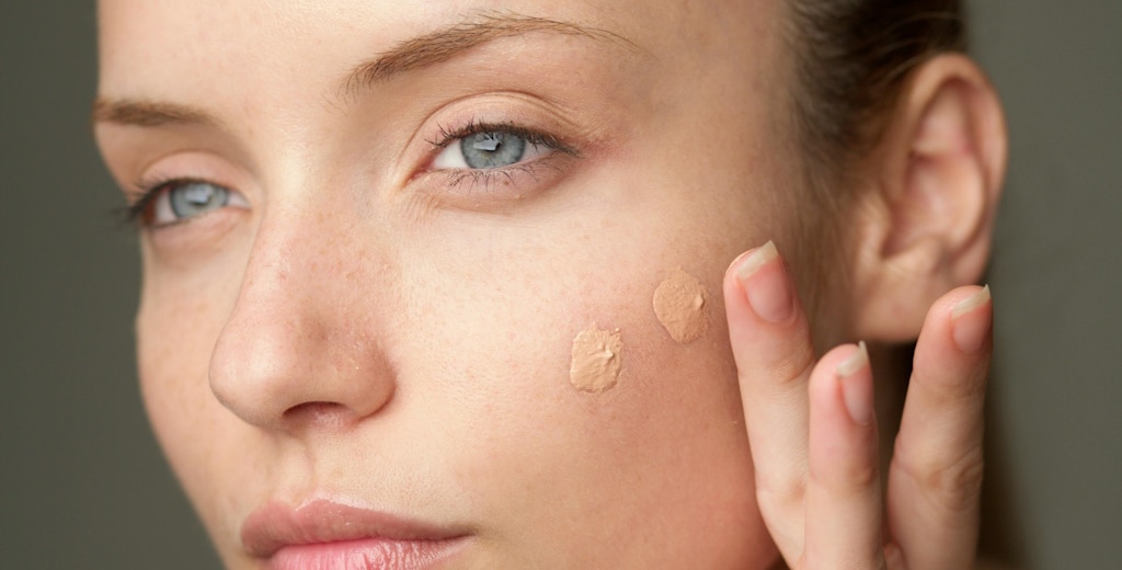 Close-up of a woman applying small amounts of foundation to her face