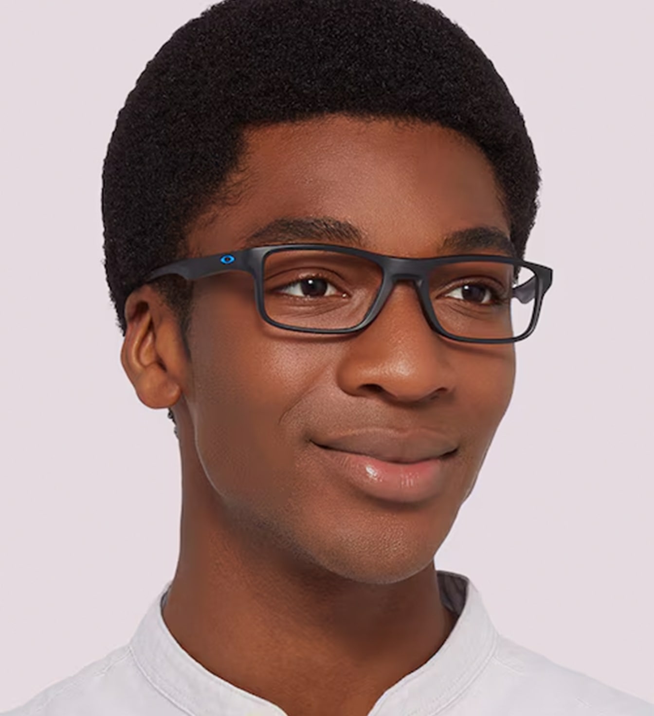 A young man with a short afro is wearing a black rectangular frame with Oakley's iconic blue-coloured 'O' visible along the temples. 