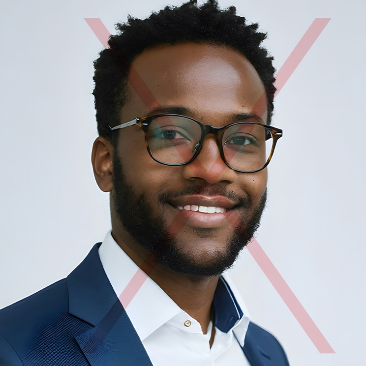 A cropped headshot of a young man with dark hair wearing a pair of round glasses, a white shirt and blue blazer. There is a red cross through the image to indicate that it's not an appropriate passport photo.