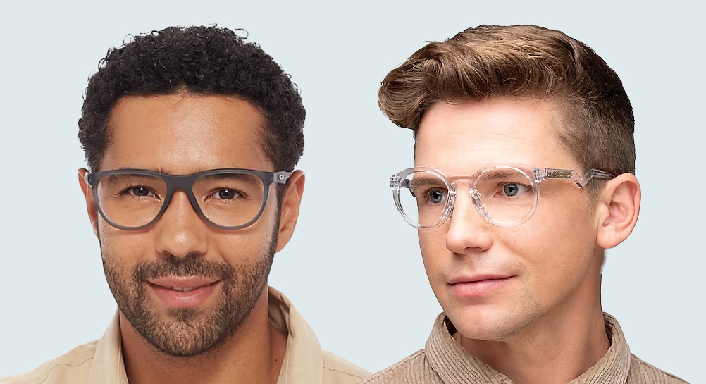 A close up shot of two young men on a white background. One has dark curly hair and stubble, he is wearing grey acetate Oakley glasses and a beige shirt. The other man is looking to one side and has a blonde quiff. He is wearing transparent Oakley glasses with a beige jacket.