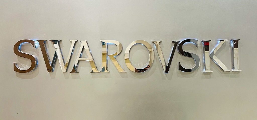 Silver metallic letters spelling out Swarovski on a light-grey background.