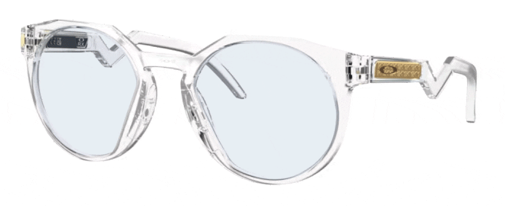 A pair of round Oakley sunglasses made of clear plastic material angled to one side, featuring blue transitioning lenses, a keyhole bridge, zig-zag temples and the Oakley 'O' logo on the arms. 