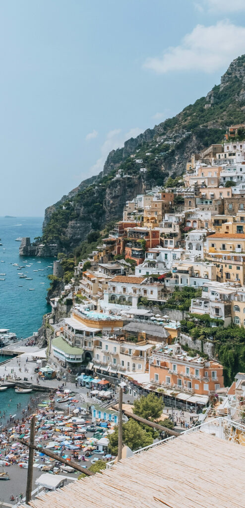 A photo of the Amalfi Coast, showing dramatic clifftops, an abundance of pastel-coloured buildings and a bright blue coastline.