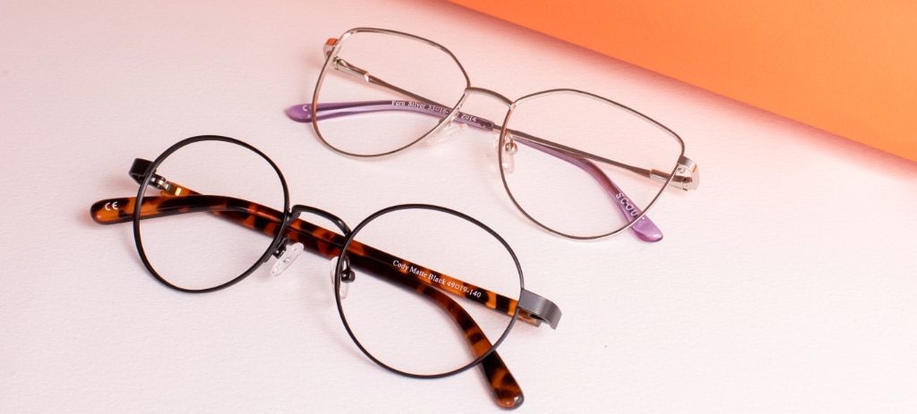 Two pairs of folded glasses rest on a white and orange background. The top pair are gold-tone metal cat-eye frames, while the bottom pair feature round metal rims paired with tortoiseshell acetate temples.
