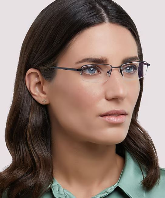 A portrait of a young woman with medium-length, dark hair against a white background. She’s wearing slim rectangular metal glasses and a mint green silk shirt, gazing off to the left.