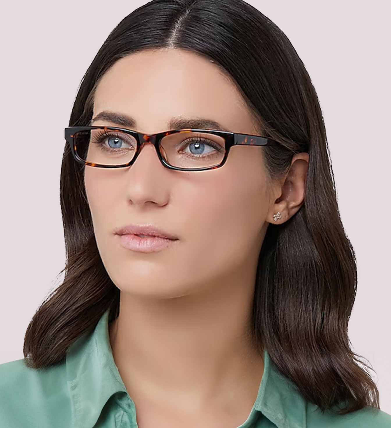 A close-up portrait of a woman, positioned to her right looking into the distance, with medium dark brown hair wearing narrow rectangular tortoiseshell glasses and a shiny mint green shirt against a plain background.
