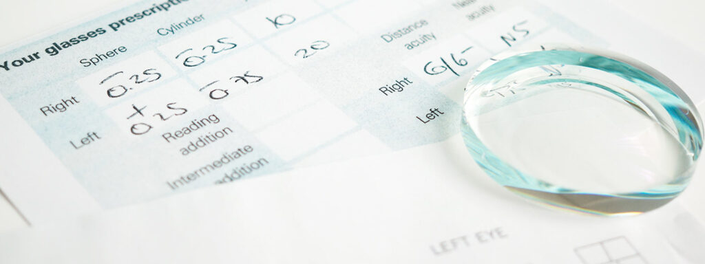 A clear lens laid flat on a filled out prescription form.