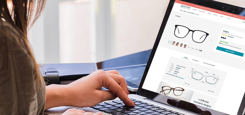 Close-up of a woman browsing glasses online on a laptop, viewing frame options and product details on the Glasses Direct website.