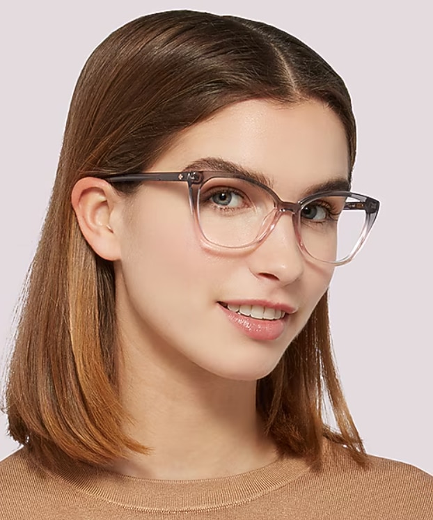 Woman with shoulder-length brown hair wearing translucent pink and grey cat-eye glasses, showcasing a stylish low-bridge fit with enhanced comfort and stability.
