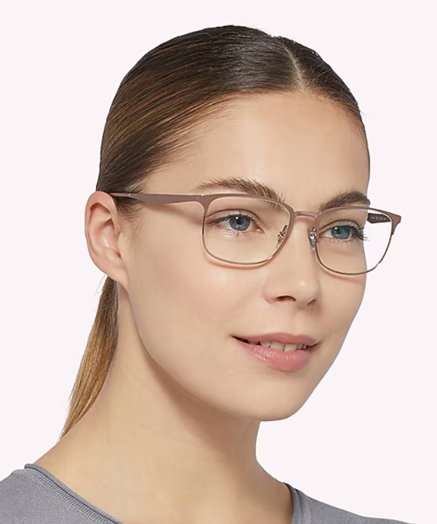 Woman with blonde hair tied back wearing Ray-Ban® RB6421 rectangular matte rose metal glasses against a neutral background.