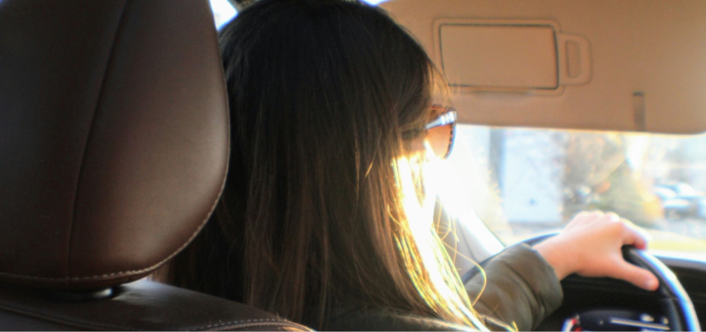 Woman wearing amber-tinted sunglasses while driving into low autumn sun.