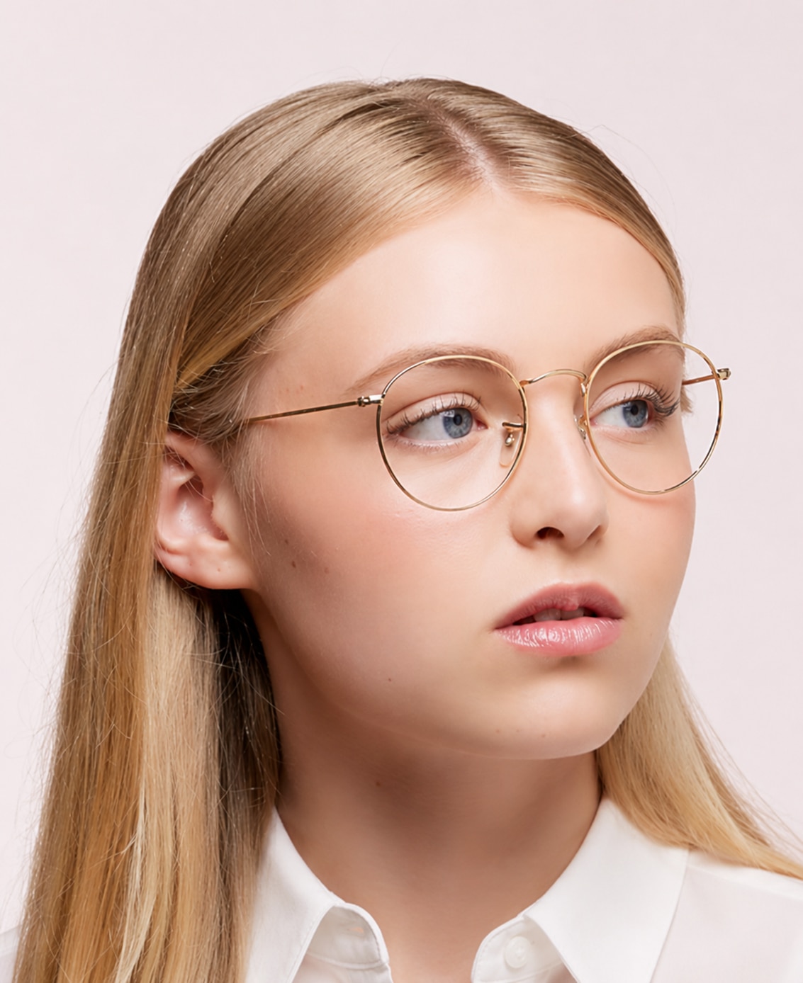 A woman with long blonde hair wearing a white shirt and Ray-Ban® RB3447V round, gold metal glasses.