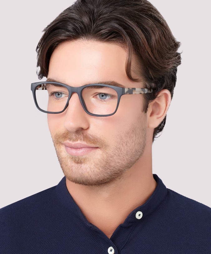 A man wearing a dark-blue shirt and The Collection Aero acetate rectangular glasses with tortoiseshell temples, on a white background.