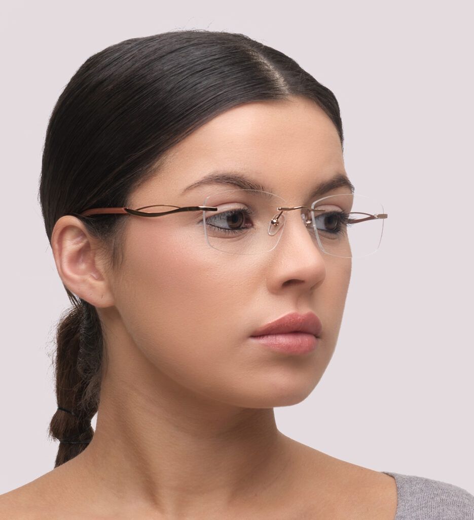 A young lady with dark hair tied in a low ponytail. She is wearing a small rimless rectangular frame with a curved design along the temples.