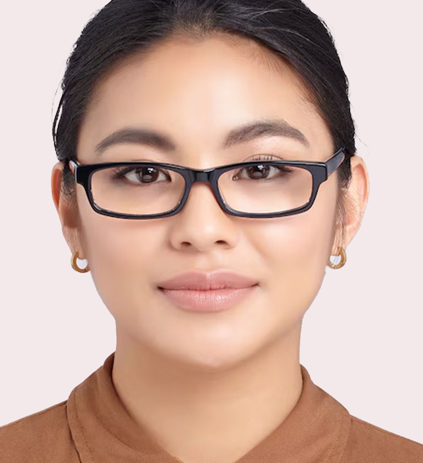 A young lady with dark hair tied neatly back in a ponytail. She is wearing a slim pair of black rectangular glasses and an orange shirt.