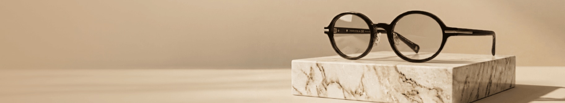 A round glasses frame poised on a small slab of marble