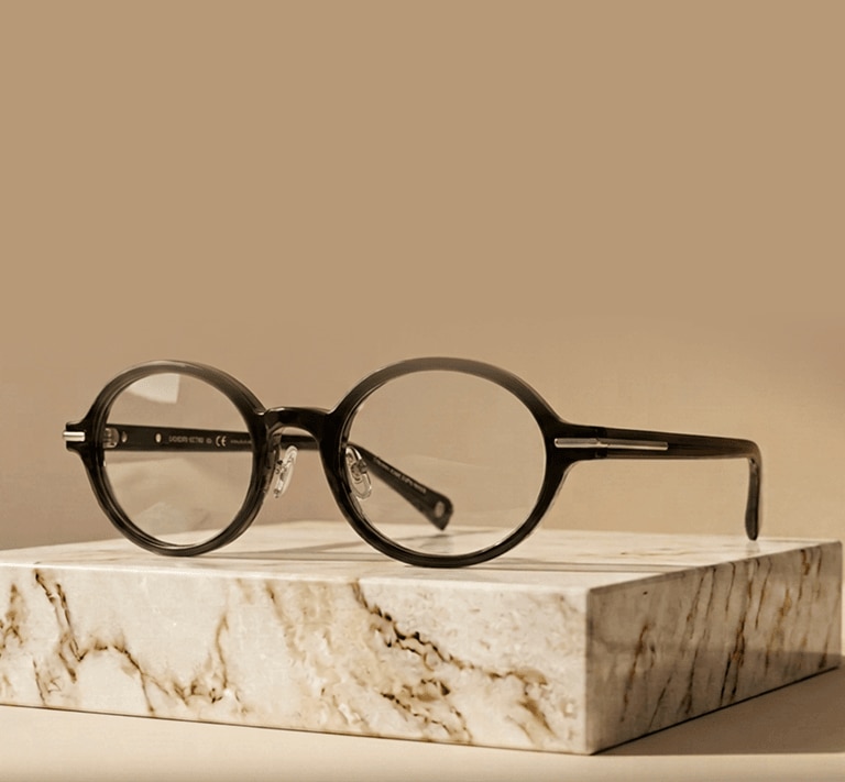 A round glasses frame poised on a small slab of marble