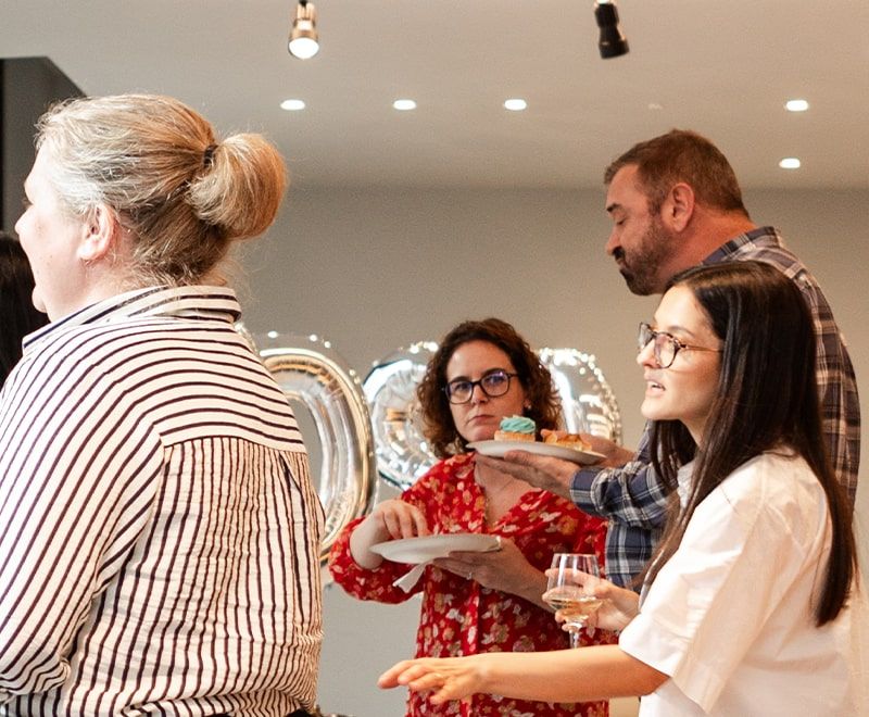 Group of male and females enjoying cake and conversing