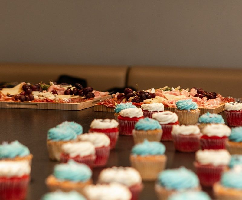 Close-up of the cupcakes and platters of meats, cheese and grapes for the party