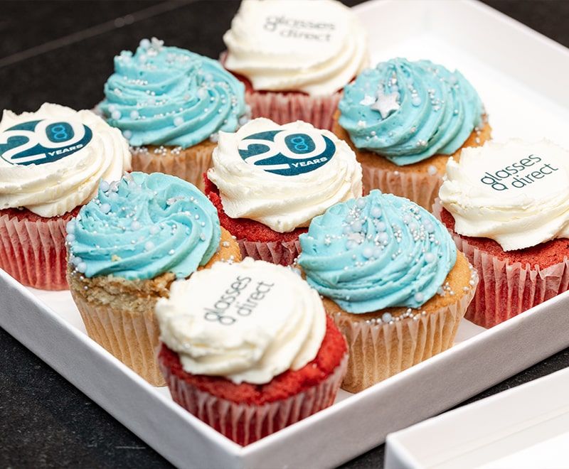 Close-up of cupcakes with blue and one icing on vanilla and red velvet sponge, with star and GD logo and 20 years badge on them