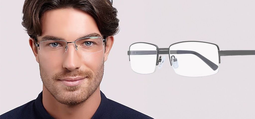 A close-up of a young man with short brown wavy hair, blue eyes and stubble. He is wearing a pair of narrow semi-rimless metal glasses and a dark-blue shirt. The same glasses are displayed closer up at an angle next to him.