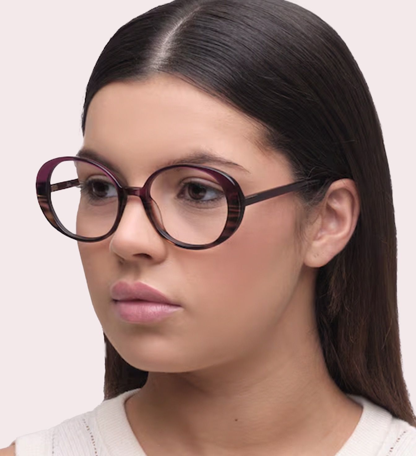 A close-up of a young lady with long, straight dark-coloured hair. She is wearing a pair of 60s-style oval glasses made of gradient brown and purple acetate.