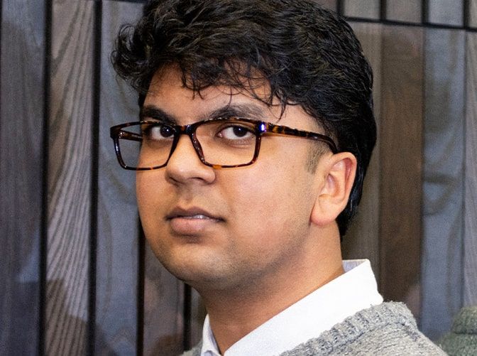 Young man with dark curly hair wearing The Collection Doran glasses