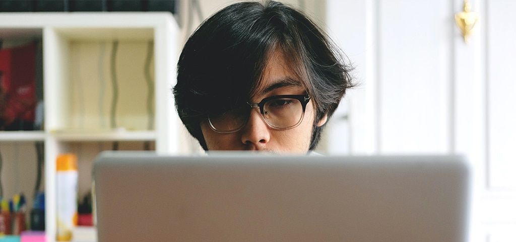 Man wearing a pair of ombre colour frames in front of a computer screen