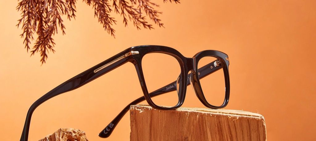 A bold black rectangular frame balanced on a chunk of wood with a bunch of heather hanging over it.