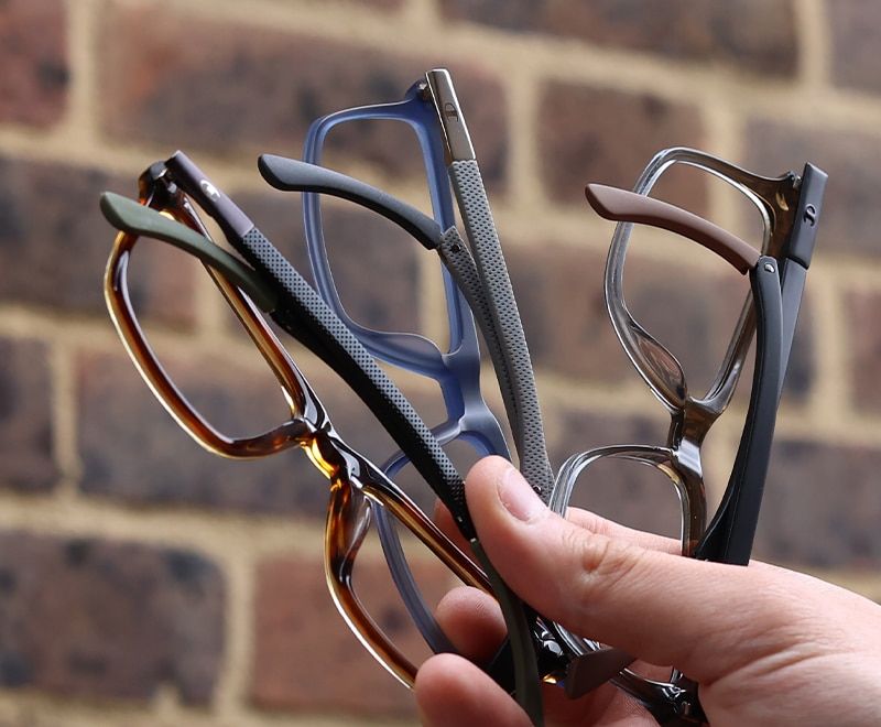 Close-up of champion frames showing the 3 stages of the bendable ear adjustments held up outdoors