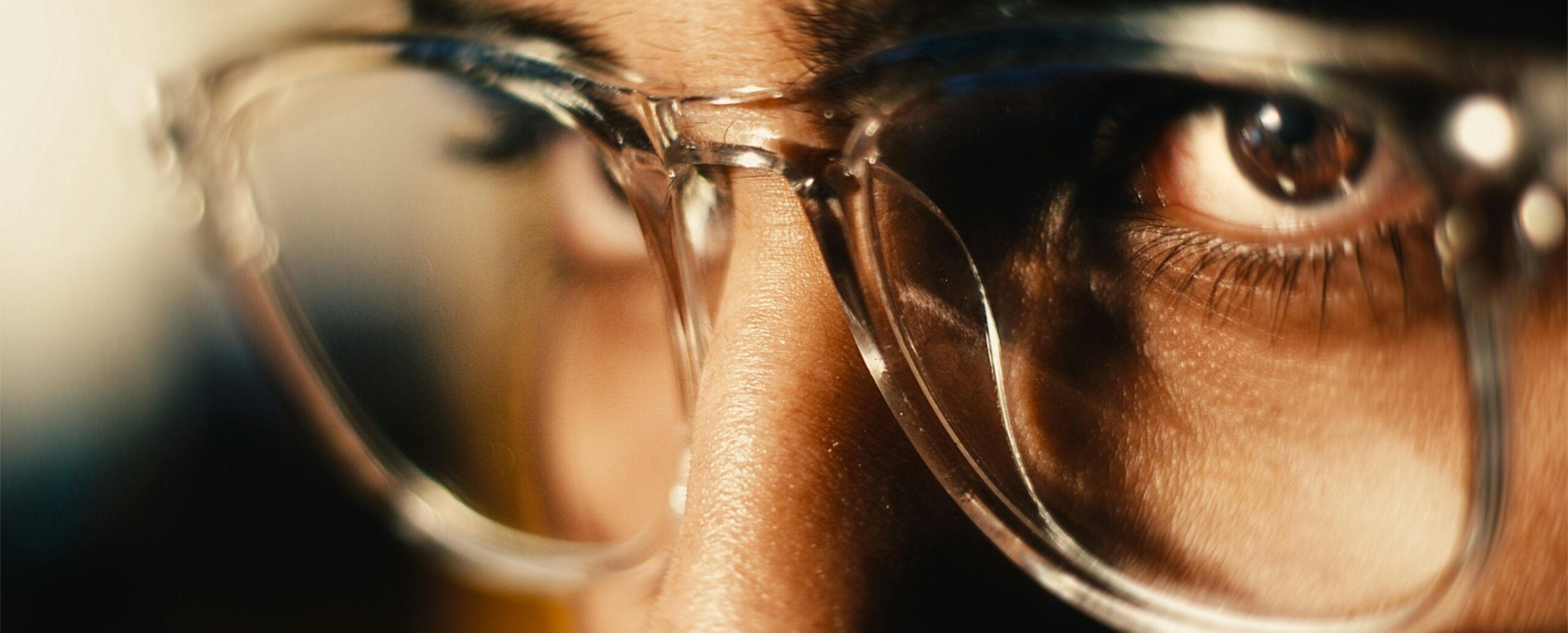 A close up from the side of a person's eyes wearing transparent glasses.