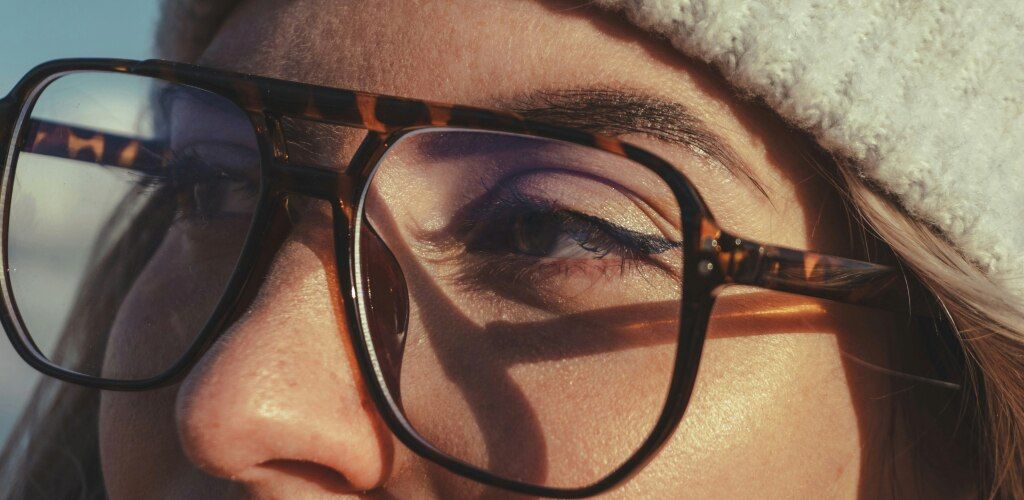 Close-up of a woman's eyes wearing tortoiseshell pilot glasses in winter sunlight.