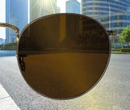 Dark brown lens with a city skyline and road visible in the background.