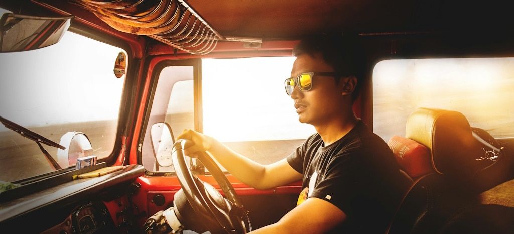 A man driving a truck while wearing Wayfarer sugnlasses