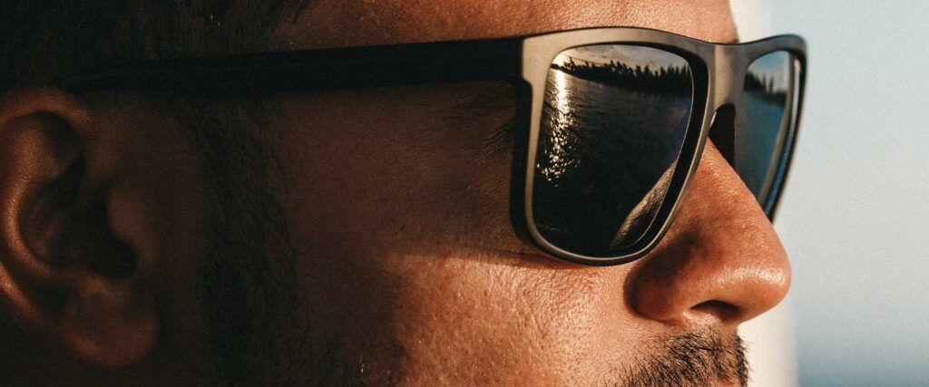 Close-up of man wearing sunglasses looking to the right into the diatance at the sea