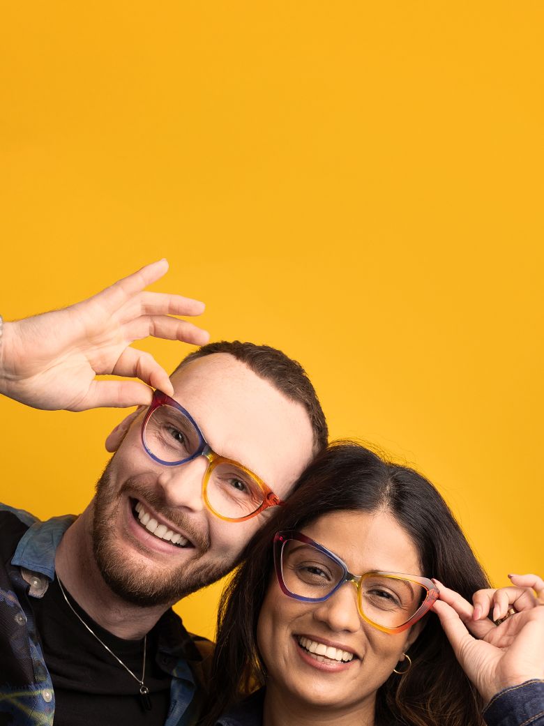A laughing couple wearing two of our 2026 limited edition Pride frames