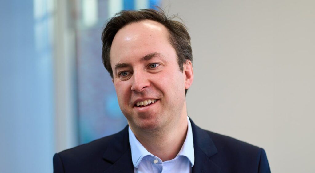 Close-up shot of Glasses Direct founder Jamie Murray-Wells wearing a suit looking to the left