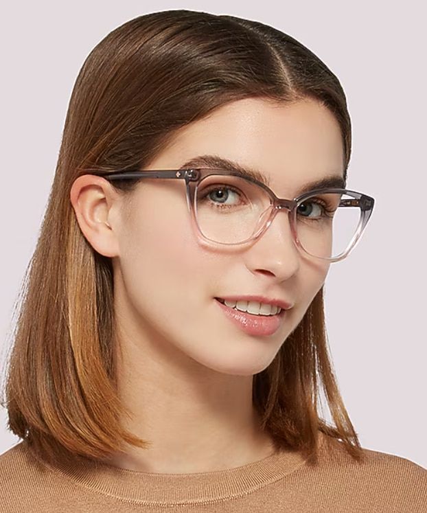 Woman with shoulder-length brown hair wearing translucent pink and grey cat-eye glasses, showcasing a stylish low-bridge fit with enhanced comfort and stability.