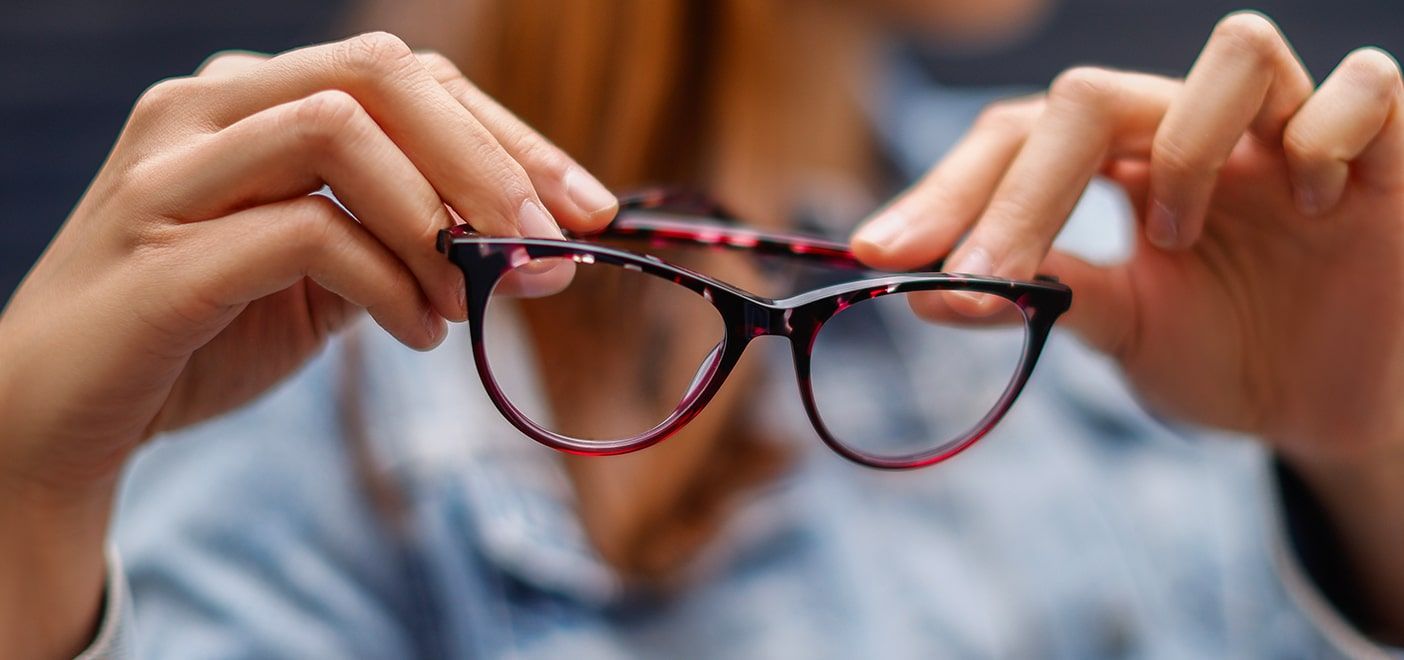 Close-up shot of a woman holding a pair of purple tortoiseshell Levi's frames