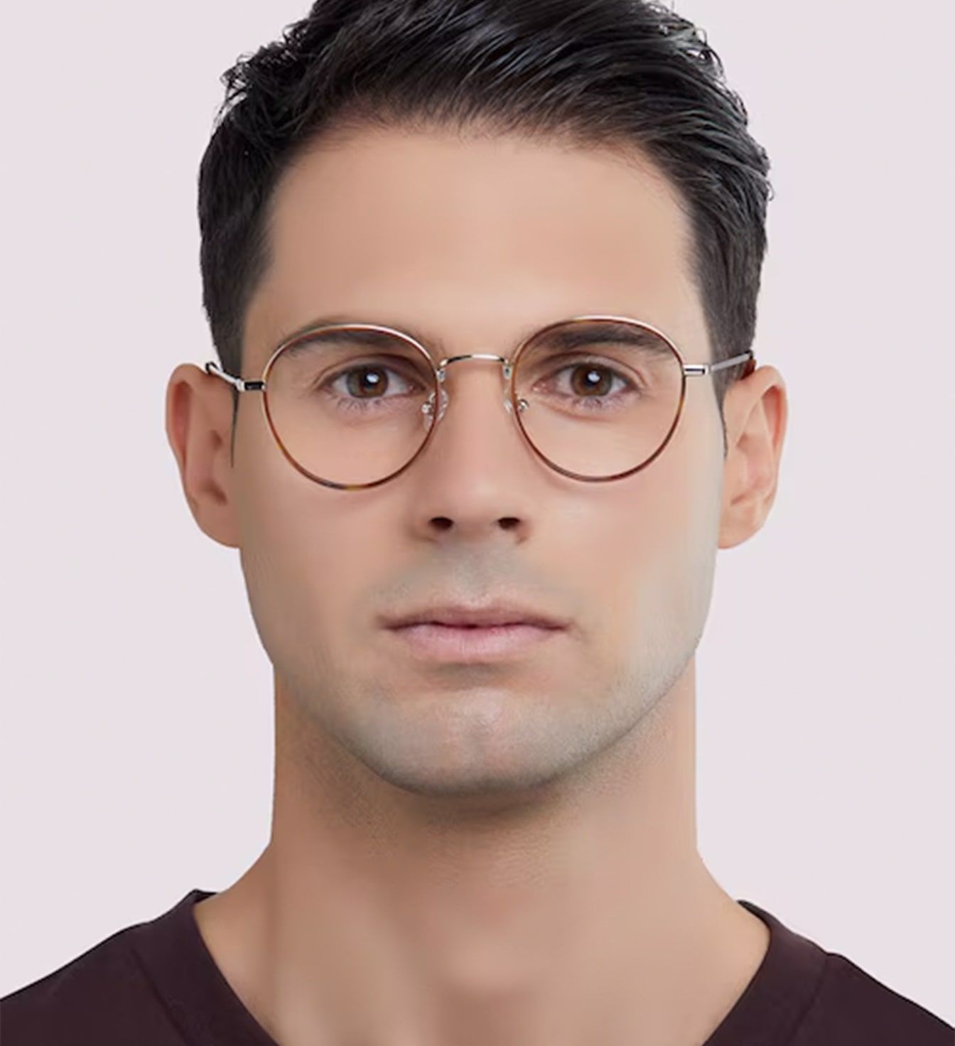 A young man with short dark-brown hair swept back. He is wearing a retro-style pair of metal round glasses and a dark t-shirt.