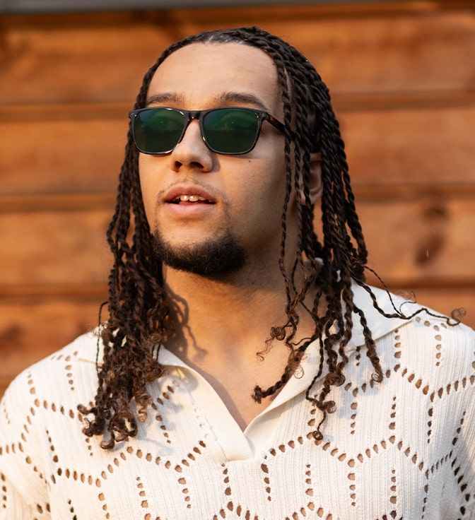 Young male wearing a pair of square, green Champion frames with Emerald Transitions tints
