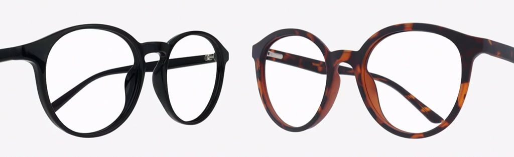 Two pairs of plastic glasses facing inwards, at an angle towards each other. The design on the left is a black phantos frame while the one on the right is a round tortoiseshell frame.