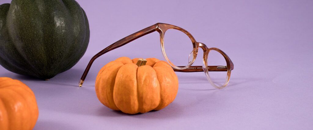 Round two-tone brown and beige ombre effect Perri Kiely xLR frames leaning on a pumpkin on a purple background